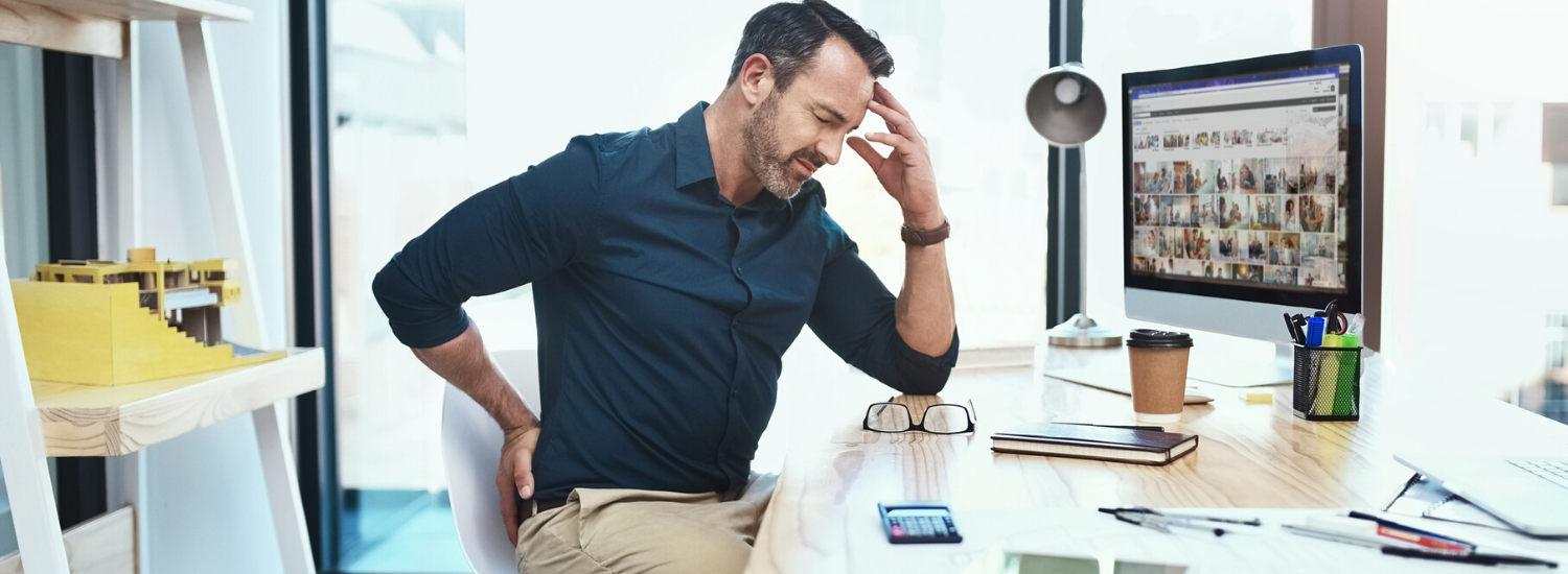 Man sitting at desk holding his back